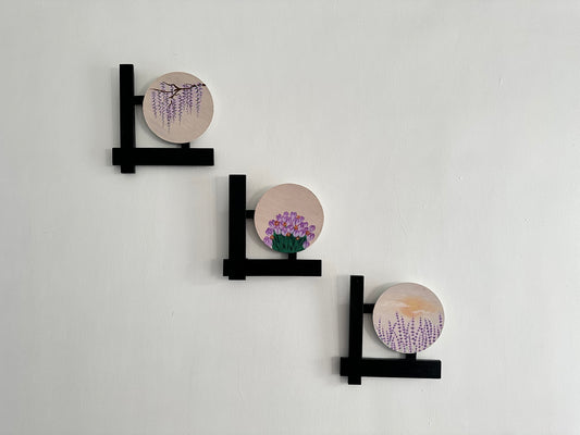 Set of 3 Floral wall hangings: Paintings on round MDF boards with black wooden L-shaped frames.